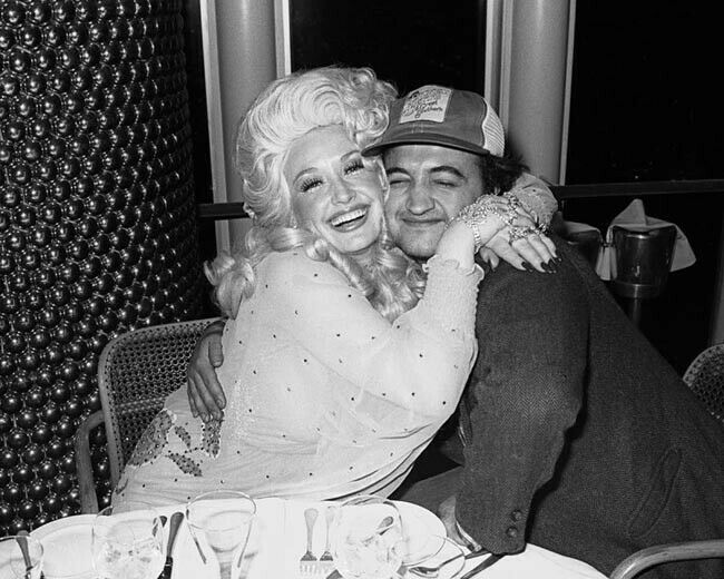 Dolly Parton Hugs John Belushi At 1980 Party 8x10 Inch Photo